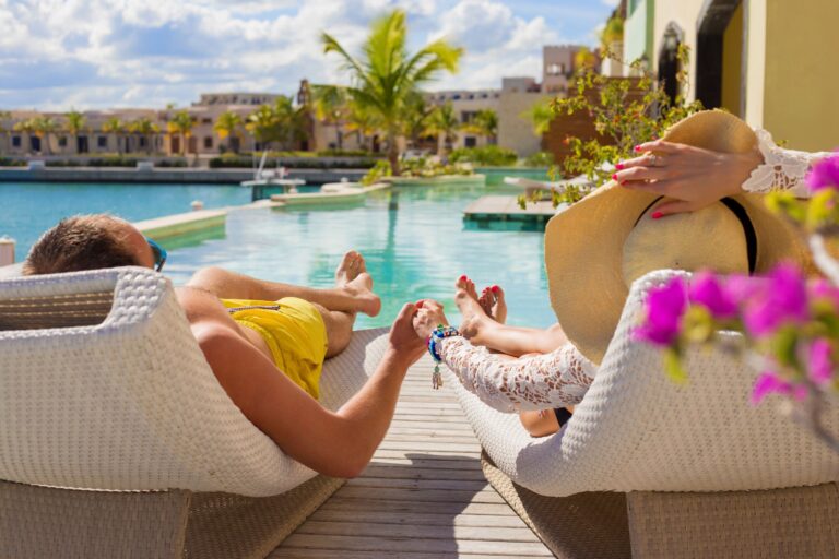 view from behind a couple in poolside lounge chairs at a resort