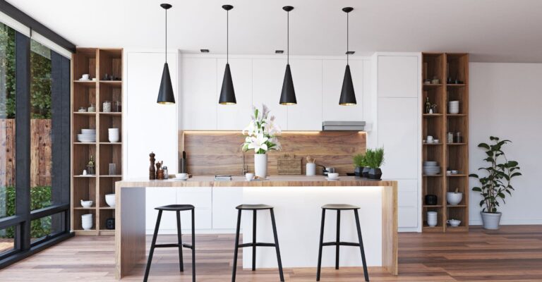 a modern, minimalist kitchen with bar stools, pendant lights and a few plants and flowers