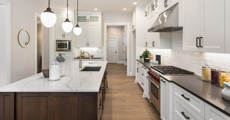 A modern kitchen featuring white cabinets and warm wood floors, creating a bright and inviting atmosphere