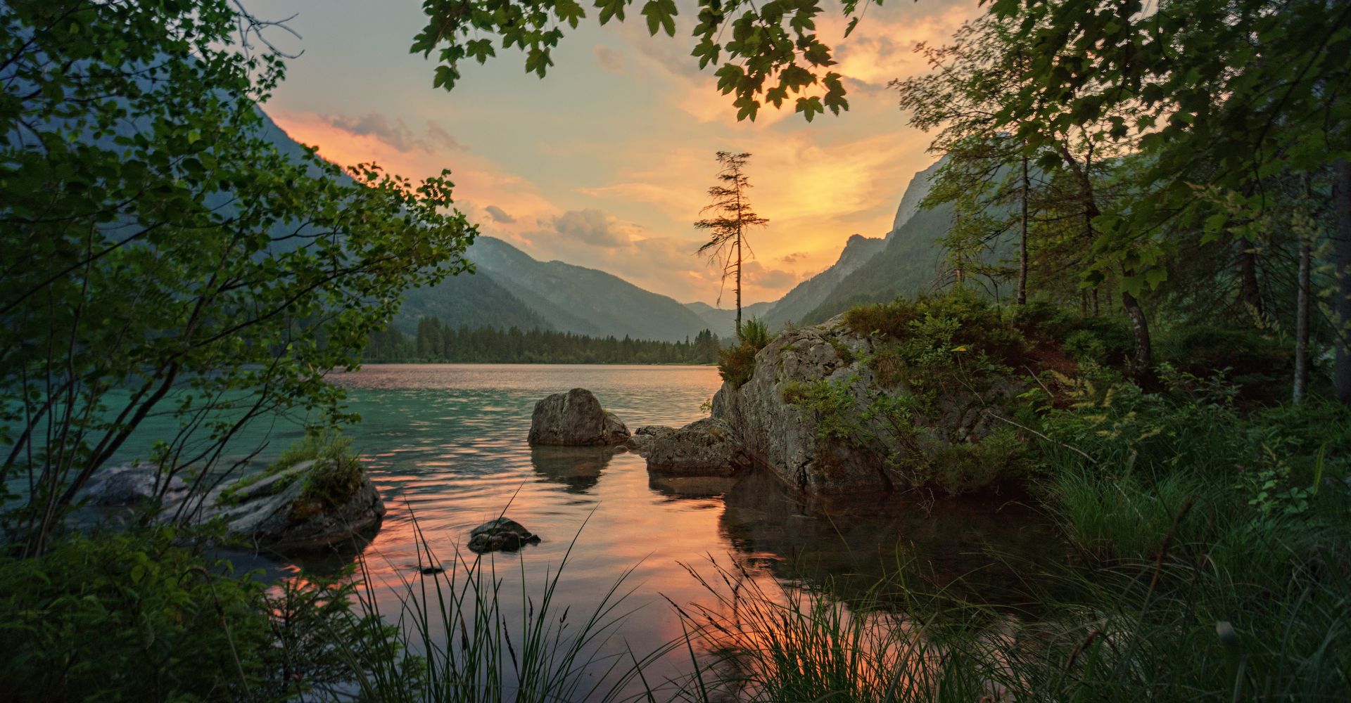 A stunning sunset casts vibrant colors over a serene Lake Tahoe surrounded by majestic mountains