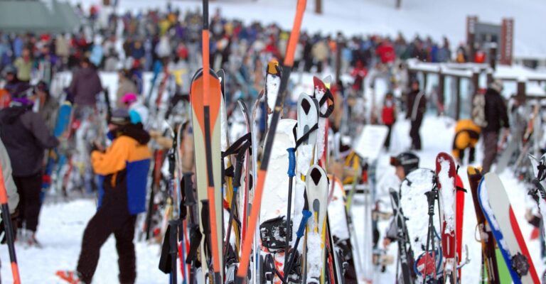 A large group of people gathered together, standing in a snowy landscape, dressed warmly for the cold weather with hundreds of skis standing up in the foreground