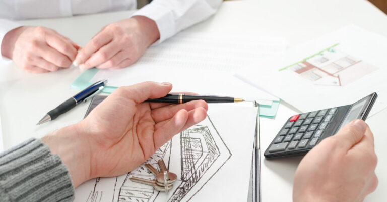 Two people collaborate on a document, using a calculator and pen to assist with their work.