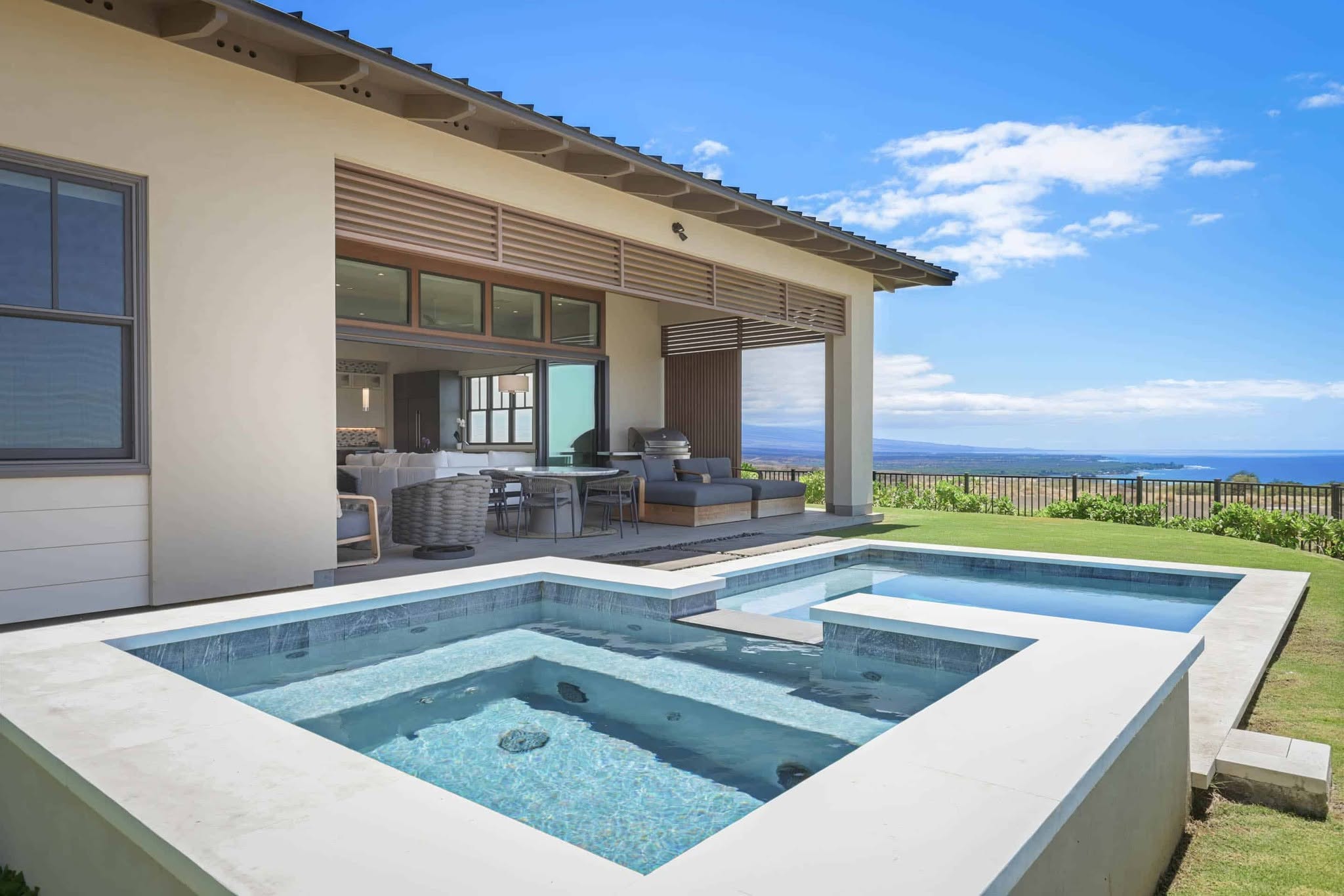 A large swimming pool overlooking a beautiful ocean view, with clear blue water and a sunny sky.