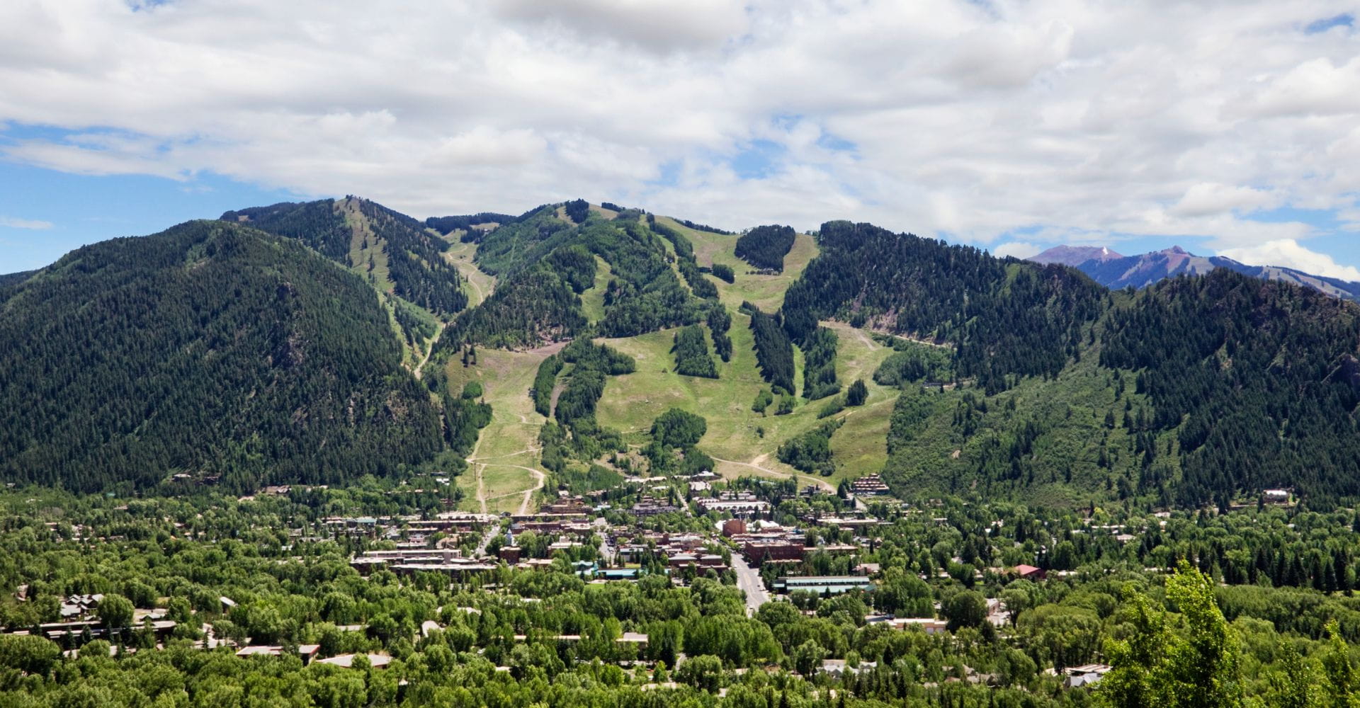 Scenic mountain town surrounded by lush green trees under a clear blue sky.