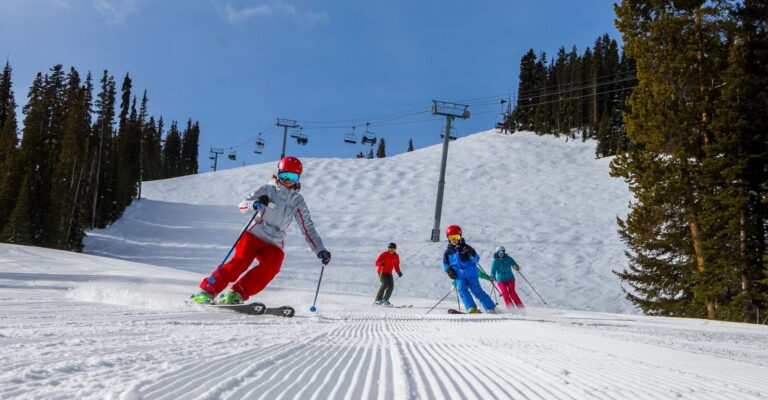 A group of skiers gracefully descending a snowy slope, enjoying a sunny day on the mountain.