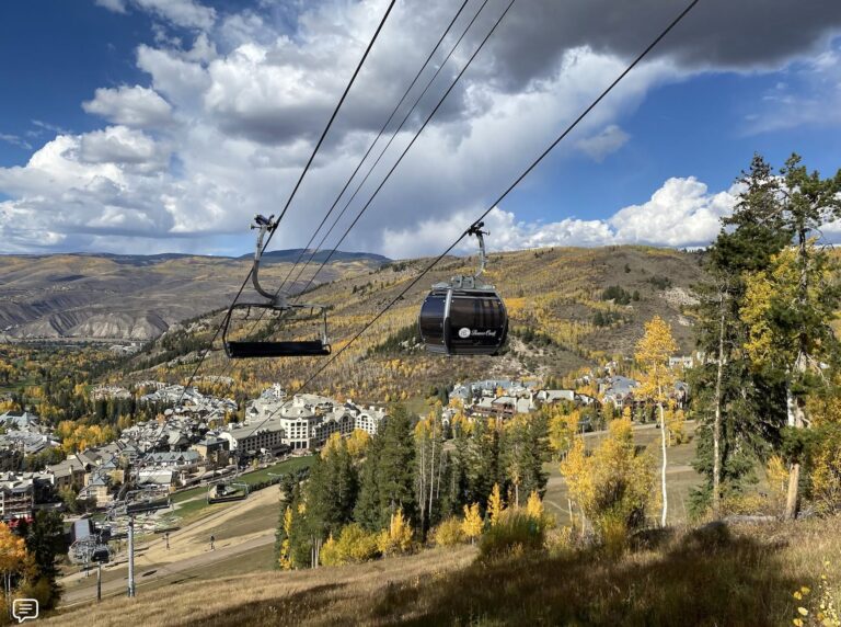 A ski lift ascends a snowy mountain, with a charming town nestled in the valley below.